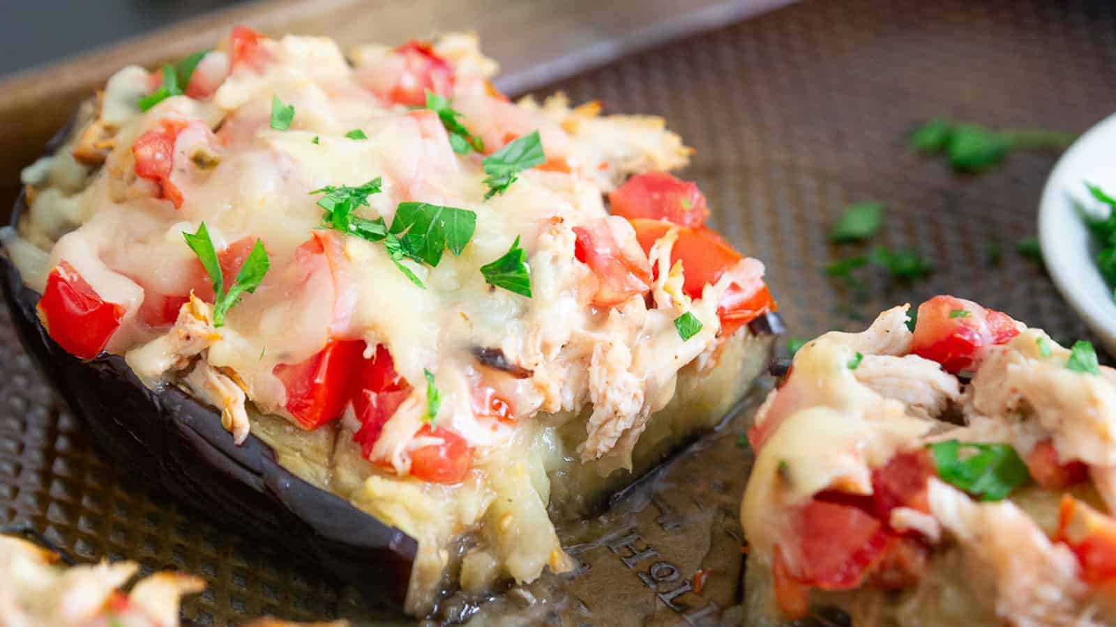 Cheesy chicken stuffed eggplant on a baking sheet.