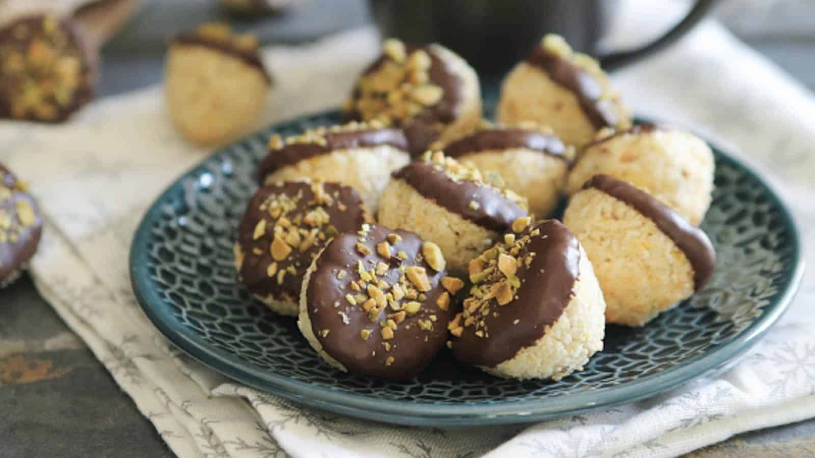 A plate of cookies with chocolate and pistachios on it.