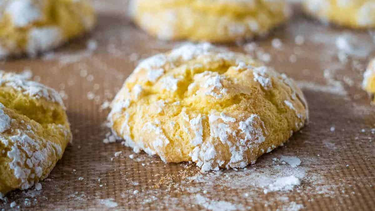 Cool whip cookies on parchment with powdered sugar.