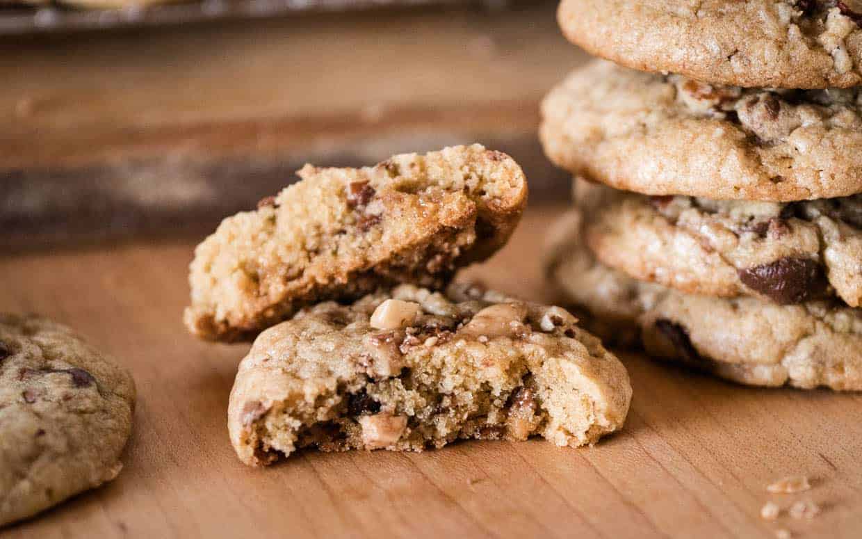 Heath bar cookies stacked up one is broken in half.