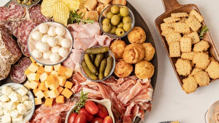 A platter of meats, cheeses and crackers on a table.