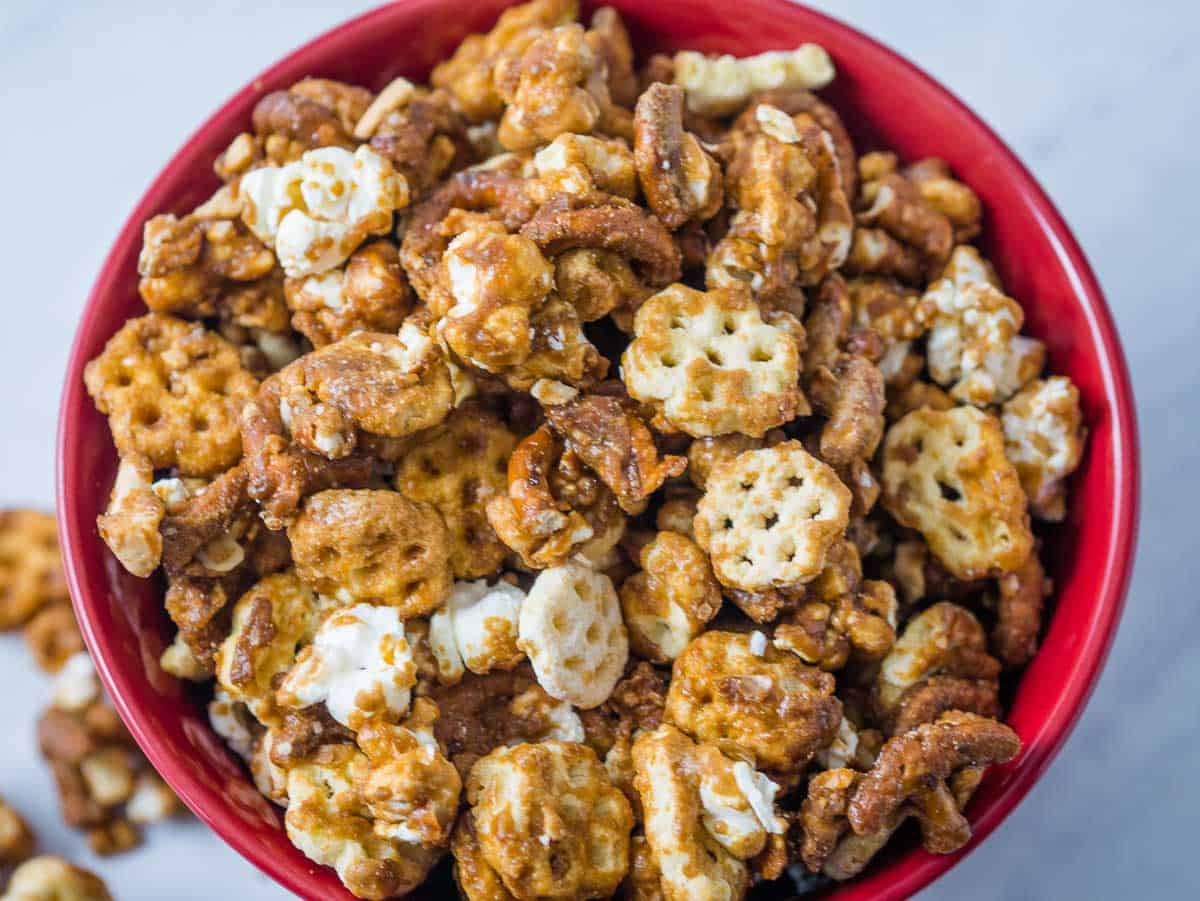 Red bowl full of honeycomb snack mix covered in caramel sauce.