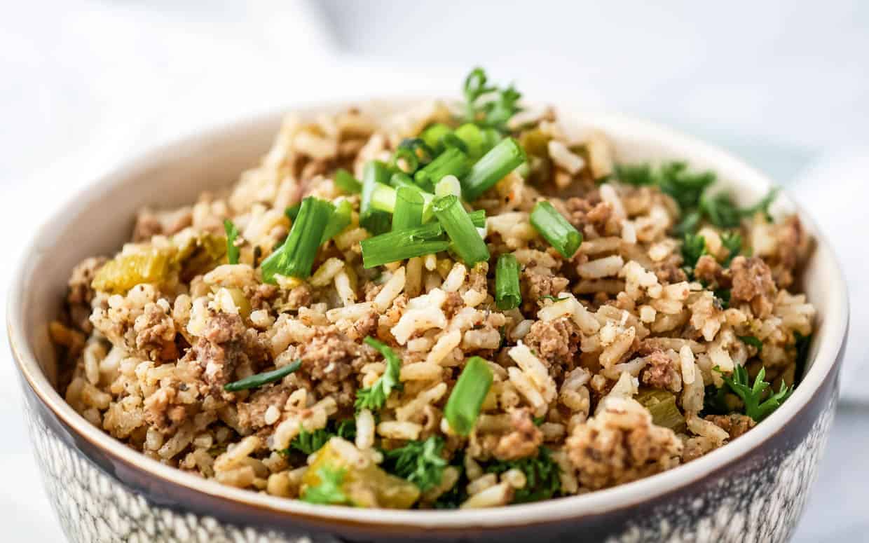 Dirty rice with ground beef in a bowl topped with green onions.