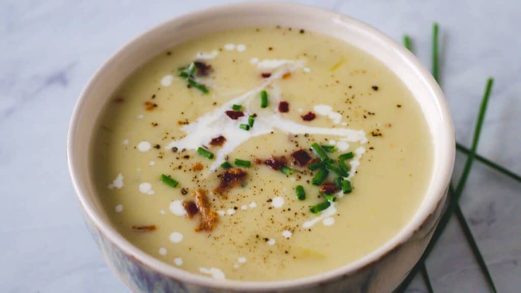 A bowl of soup with bacon and chives.