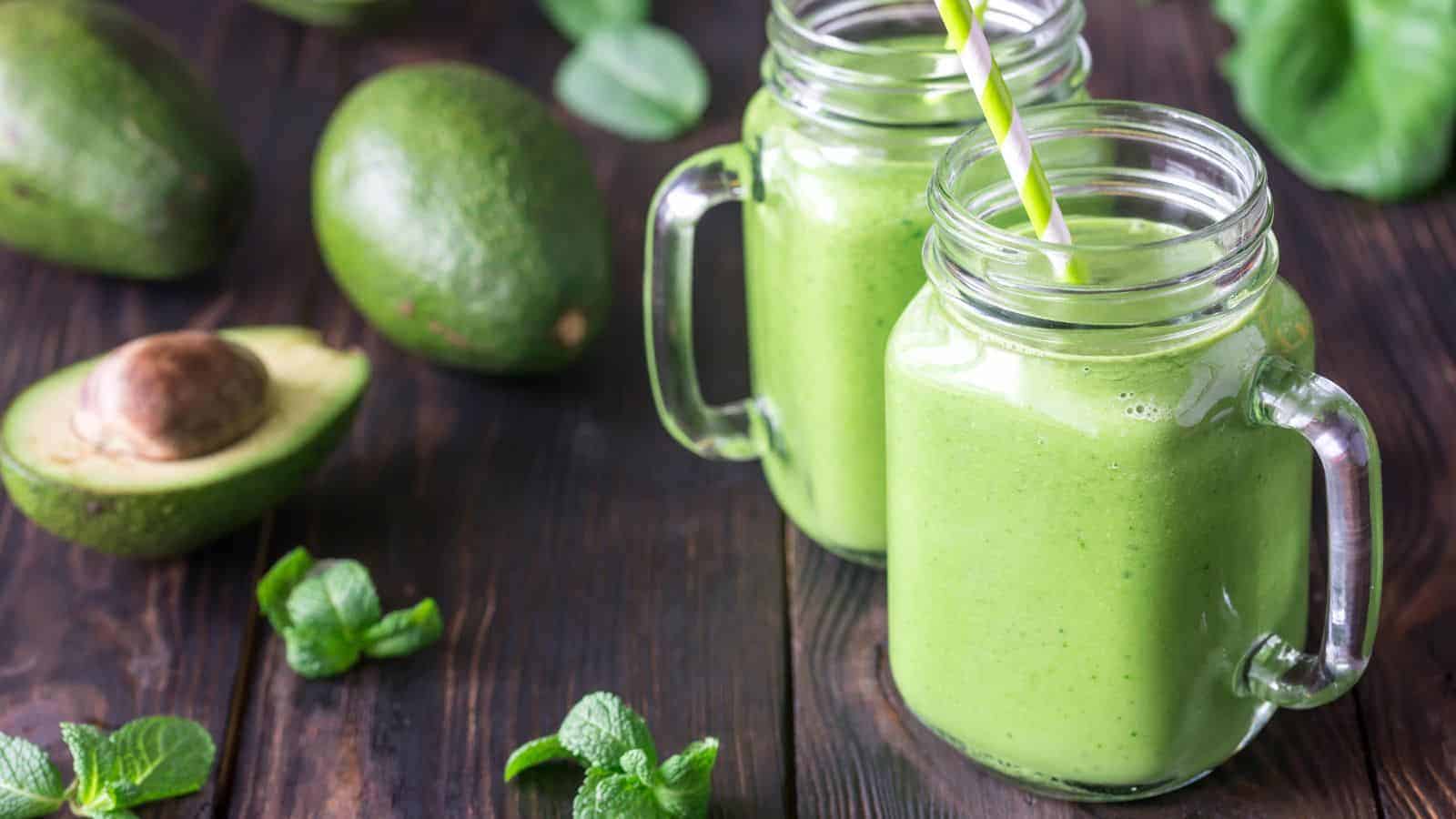 Two jars of green smoothie, a refreshing and easy breakfast option, rest on a rustic wooden table.