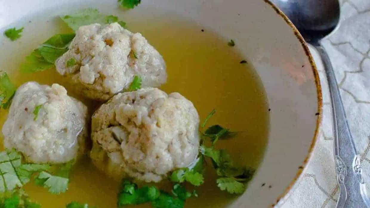 A bowl of soup with meatballs in it.