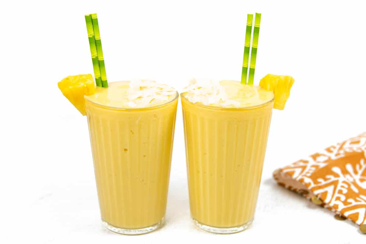 Two glasses of easy pineapple smoothie with straws.