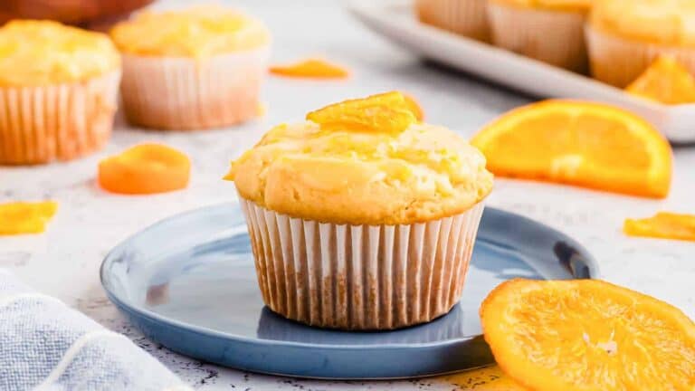 Orange muffins on a blue plate with orange slices.