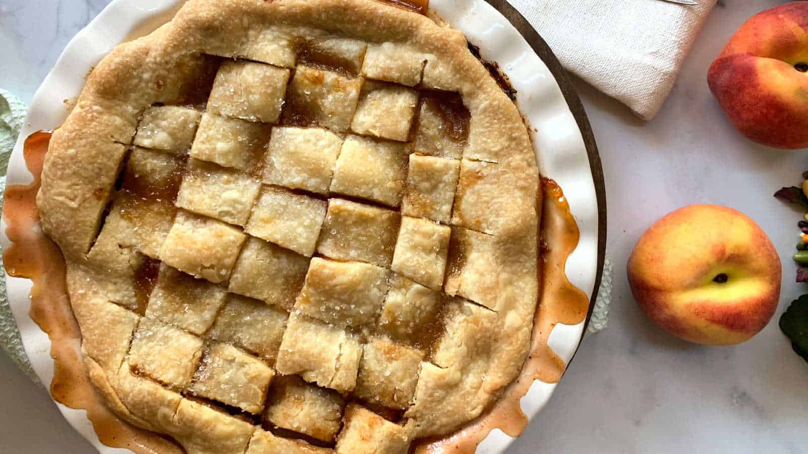 Overhead shot of peach pandowdy with fresh peaches.