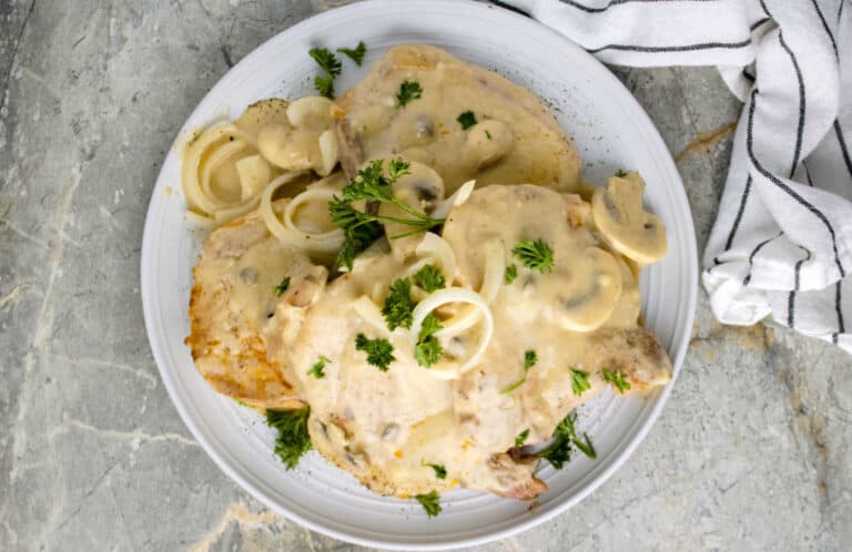 A white plate with mushrooms and sauce on it.