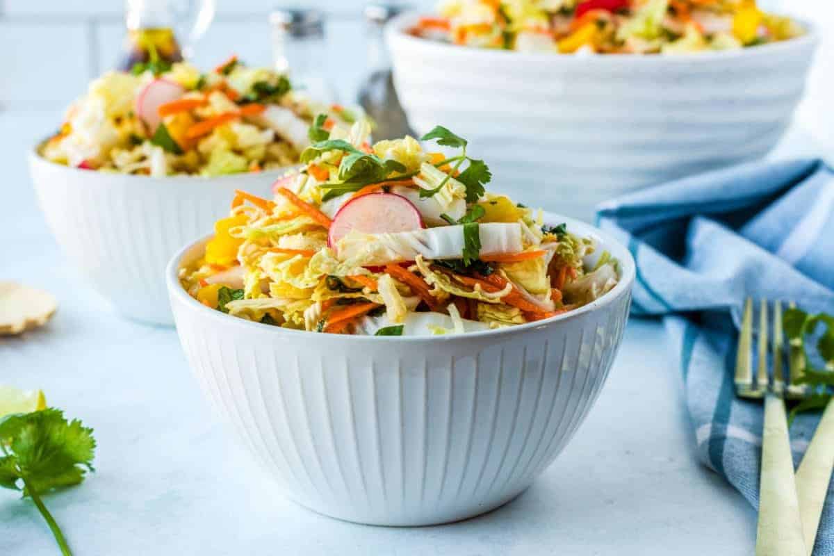 Three white bowls filled with ramen noodles and vegetables.