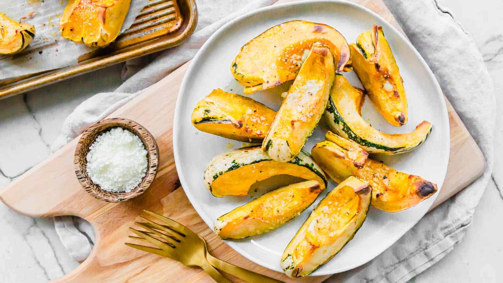 Roasted carnival squash on a white plate with a fork.