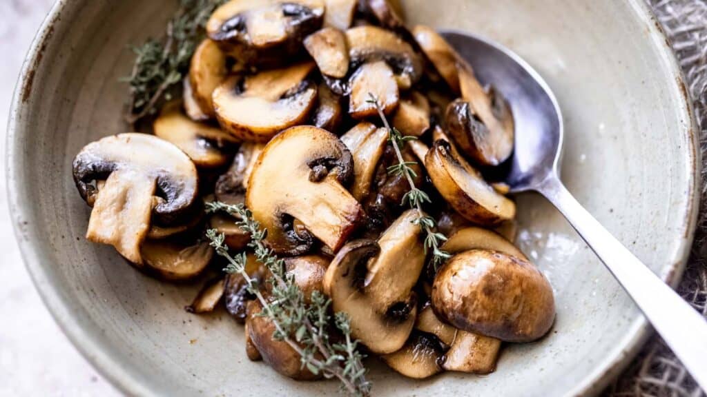 Mushrooms in a bowl with sprigs of thyme.