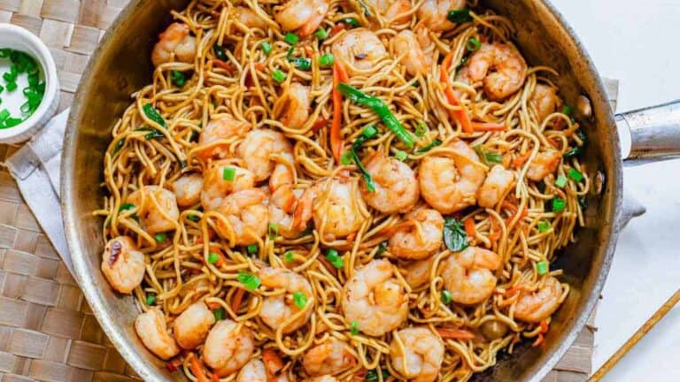 A skillet filled with shrimp and noodles.