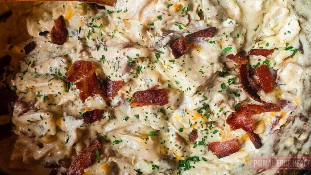 A picture of cheesy chicken with bacon and dried parsley.