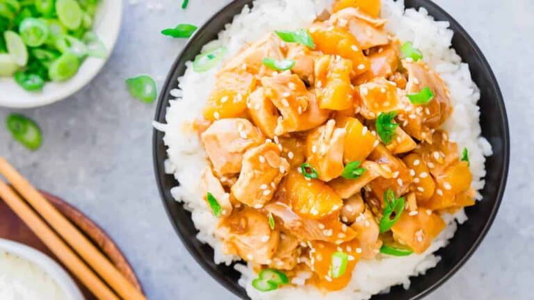 A bowl of asian chicken and rice with chopsticks.