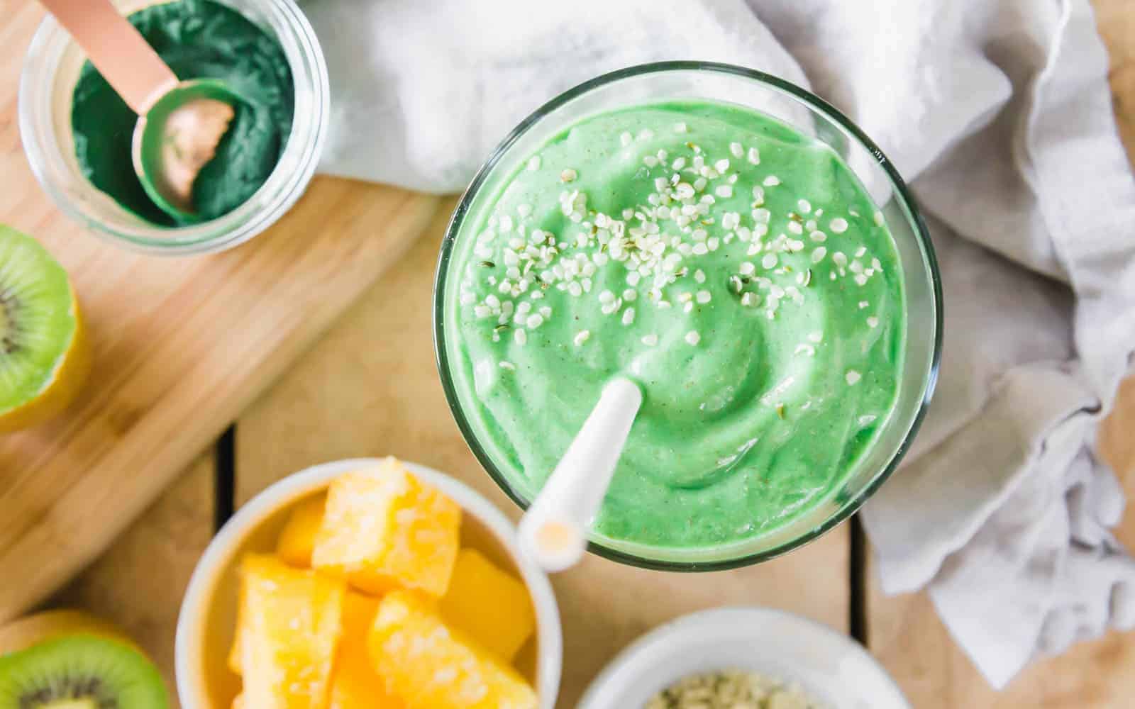 Spirulina smoothie in a glass with hemp seeds and straw.