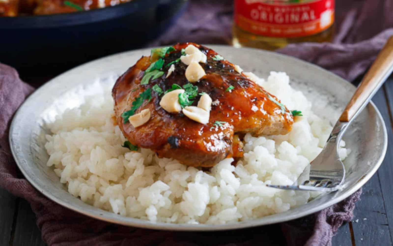 Thai chicken with sticky glaze and peanut garnish over white rice.