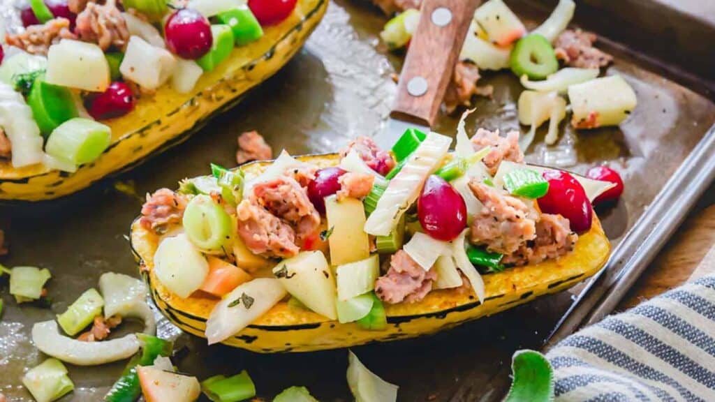 Stuffed squash boats with cranberries and meat on a baking sheet.