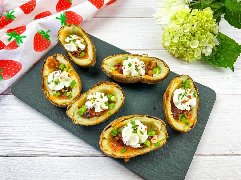 Four potato skins topped with cheese and sour cream, perfect for tailgating.