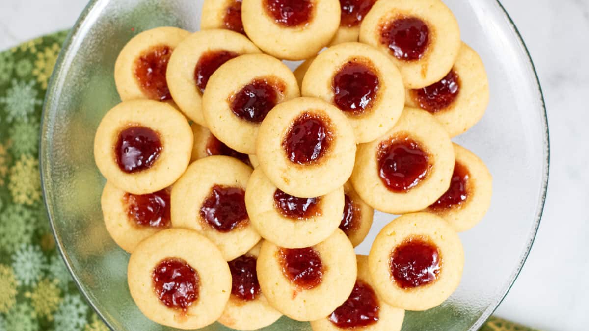 Stack of thumbprint cookies on a white plate.