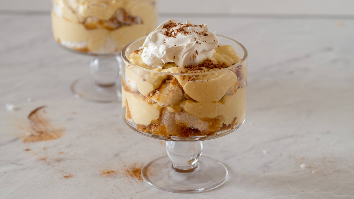 Layers of cake, coffee pudding and whipped cream in a trifle glass.