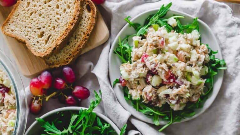 A bowl of tuna salad with grapes and bread.