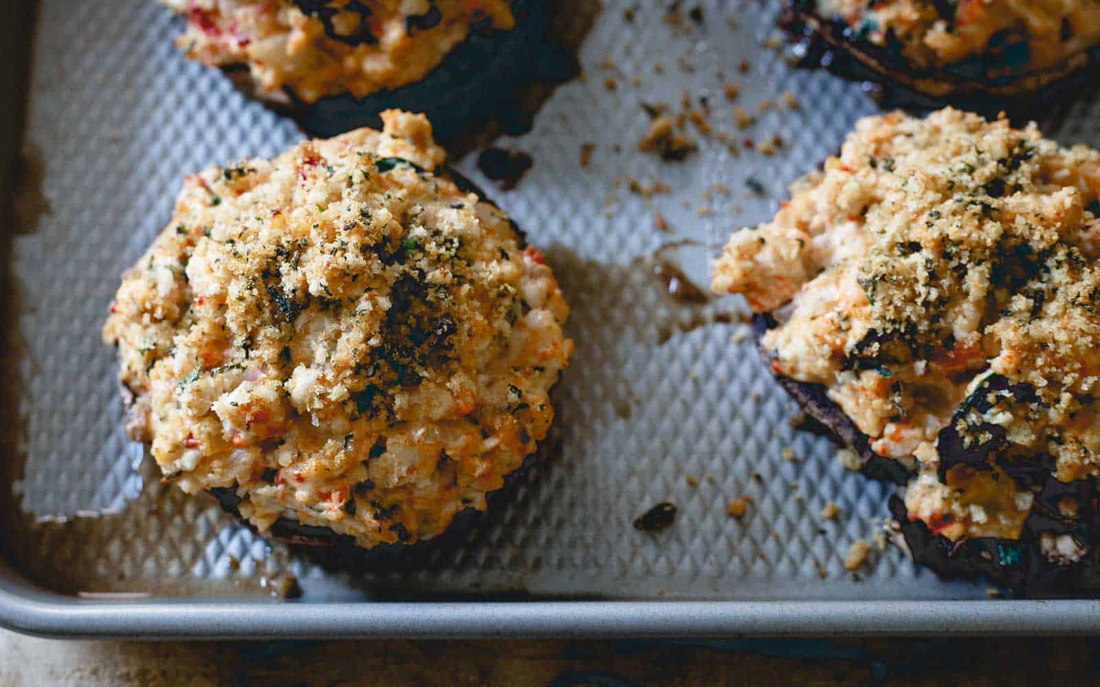 Turkey and cheese stuffed portobello mushrooms on a baking sheet.