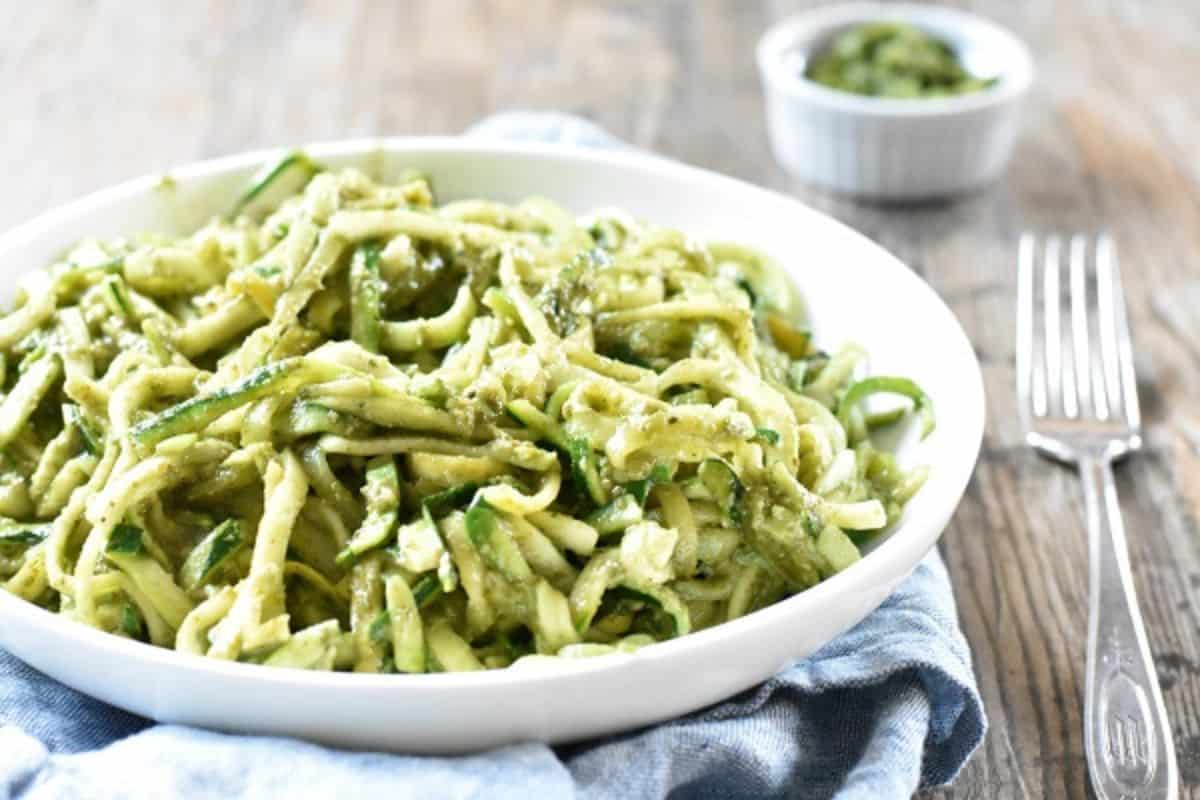 Zucchini pesto pasta in a white bowl with a fork.