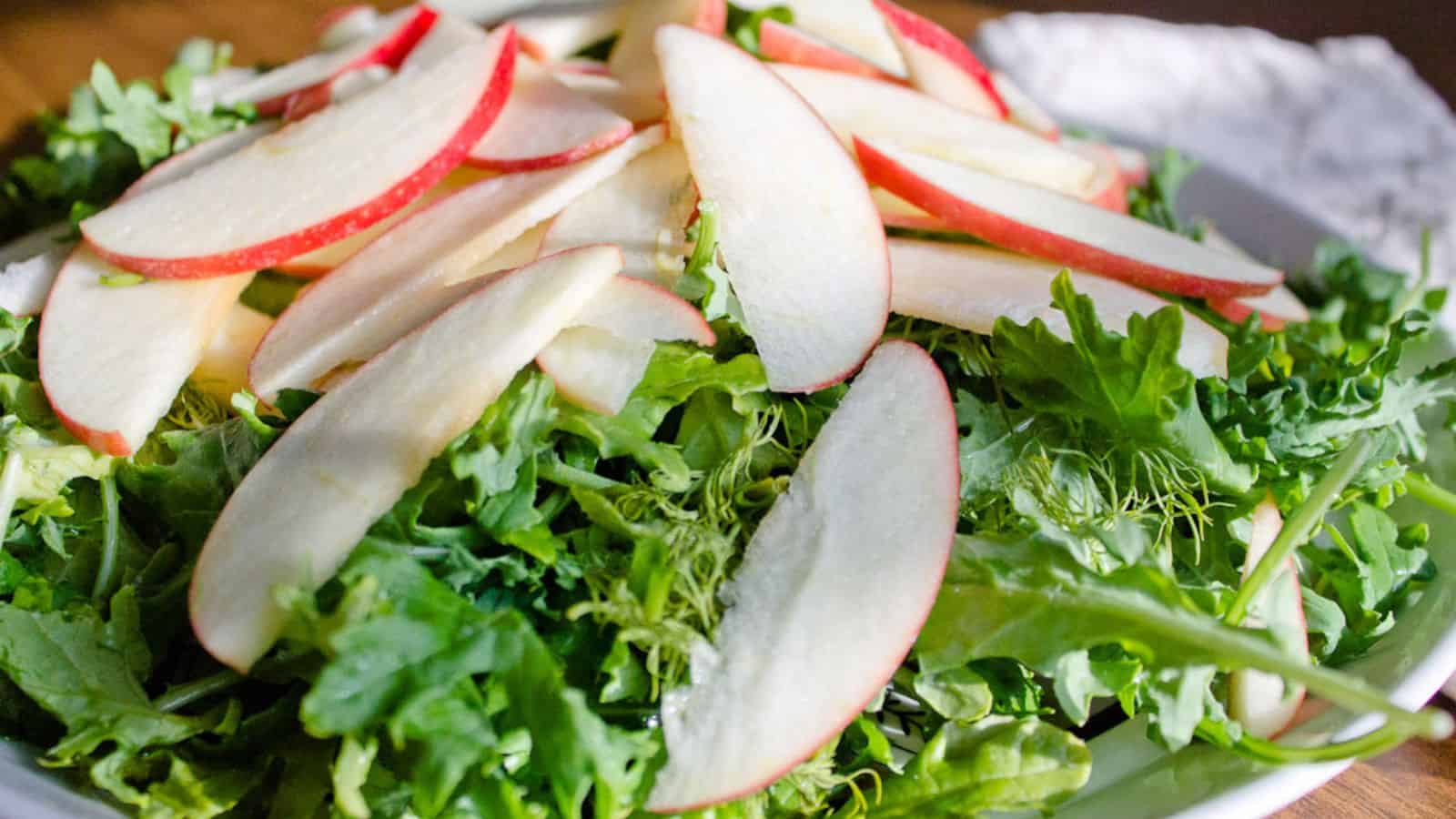 A salad with apples and kale on a plate.