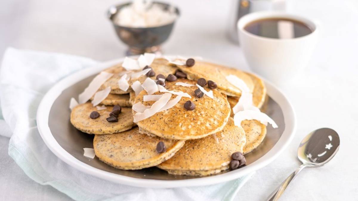 A plate of pancakes with chocolate chips and a cup of coffee.