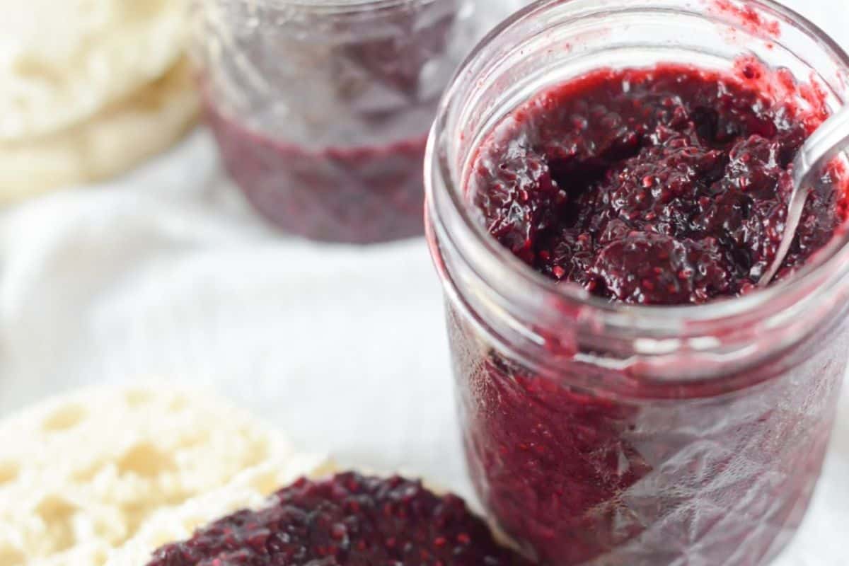 A jar of jam with a spoon next to it.