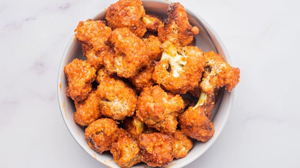 Fried cauliflower in a bowl on a marble table.