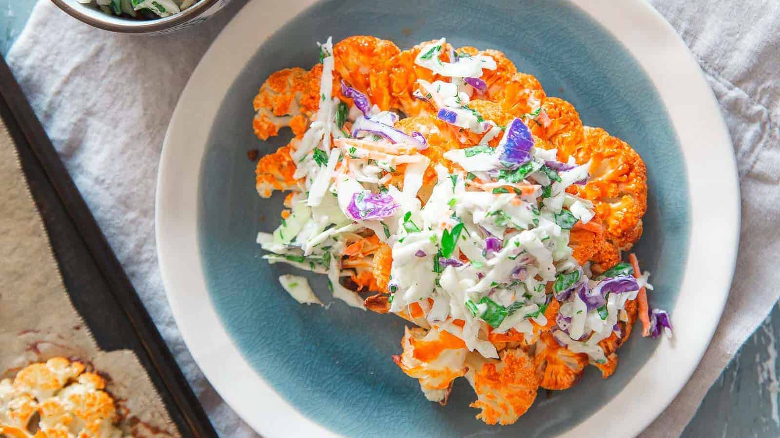 Buffalo cauliflower streaks with blue cheese coleslaw on a plate.