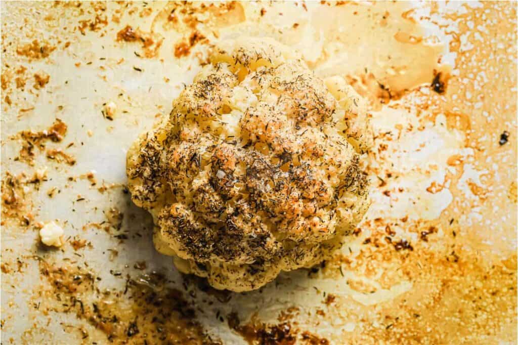 Roasted whole cauliflower on a baking sheet.