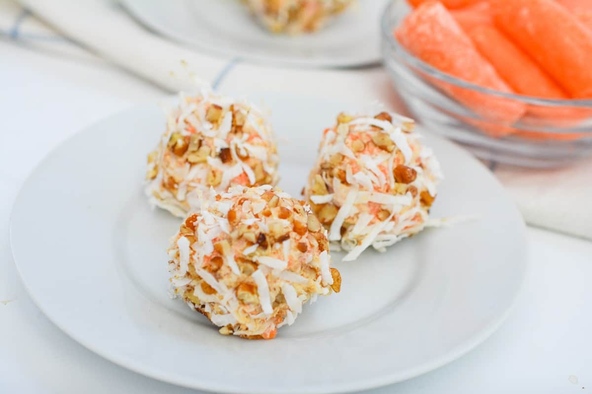 Carrot balls on a plate next to carrot sticks.