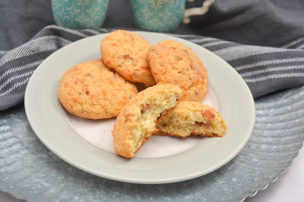 Four biscuits on a plate with a cup of coffee.