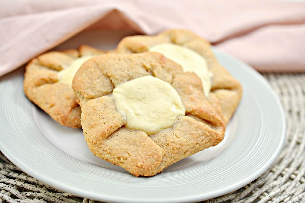 A white plate with two cheese Danish on it.