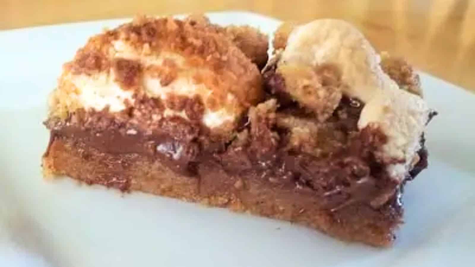 Image show a closeup of a Chewy Smores bar on a white plate.