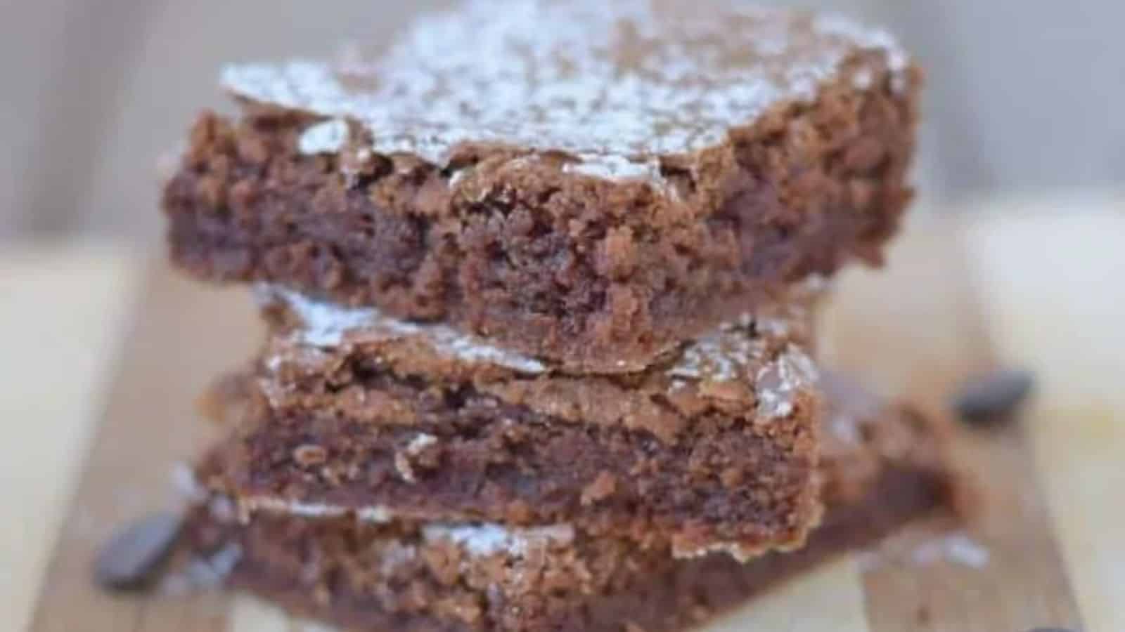 Image shows a stack of Classic Brownies on a wooden table.