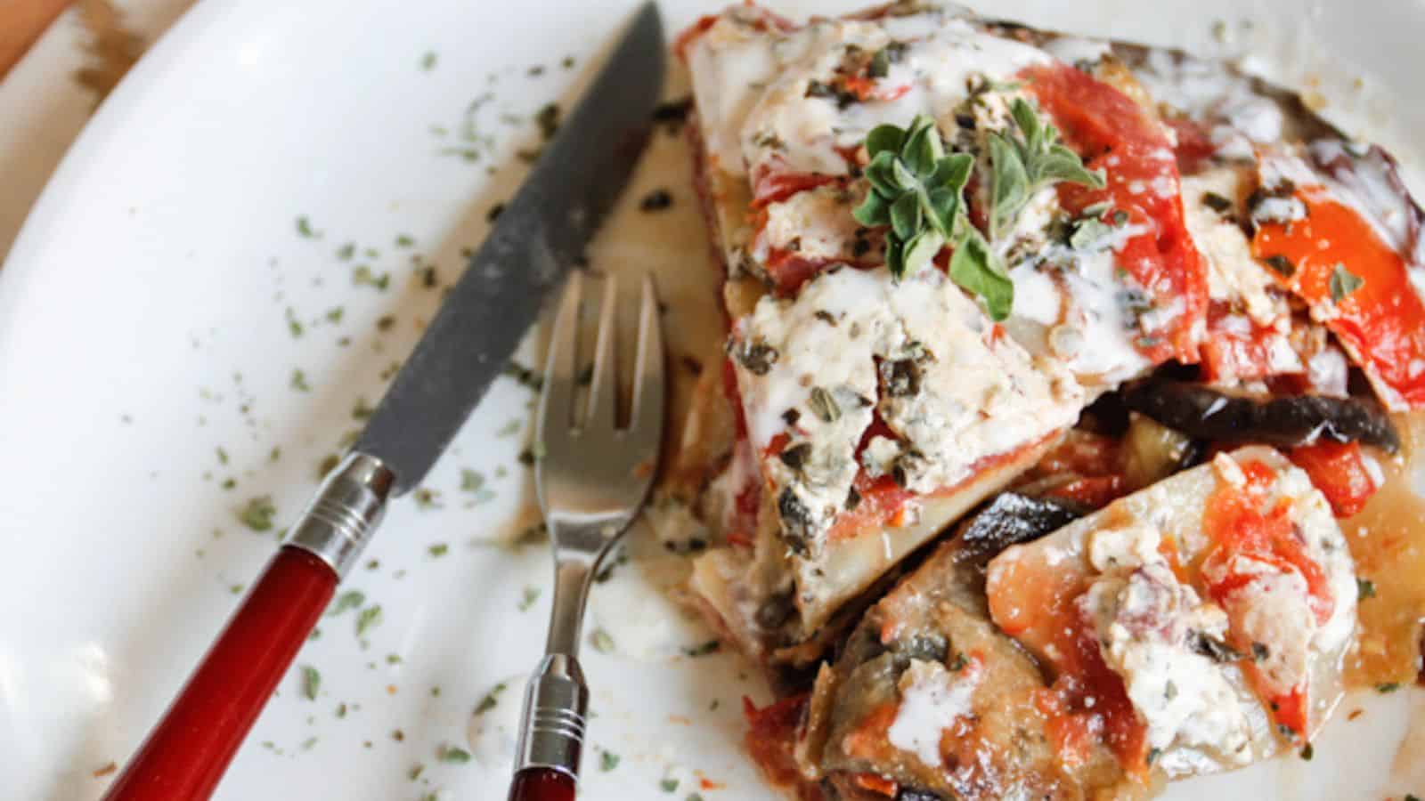 A plate with a slice of moussaka and a fork.