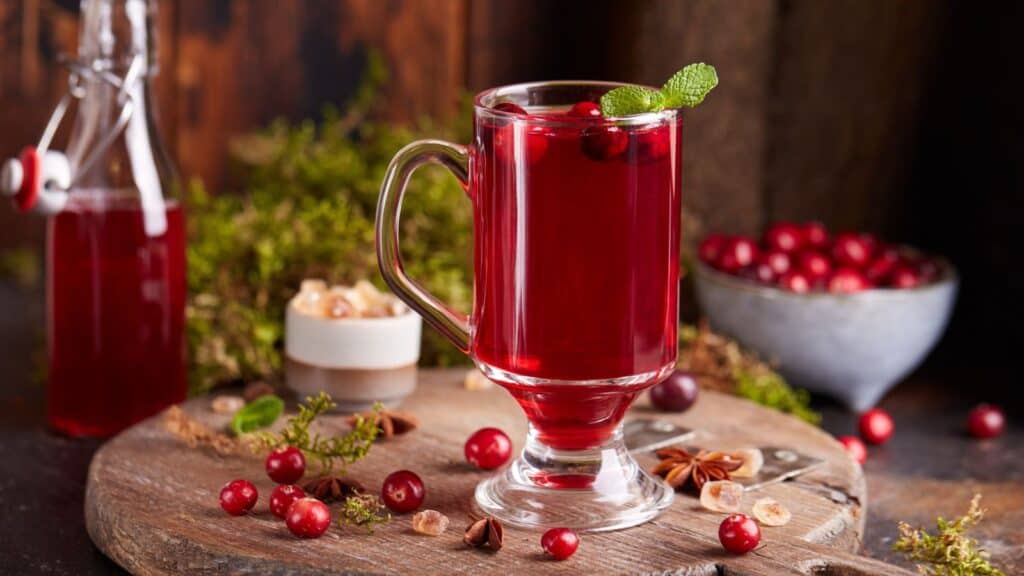 A glass of cranberry juice on a wooden table.