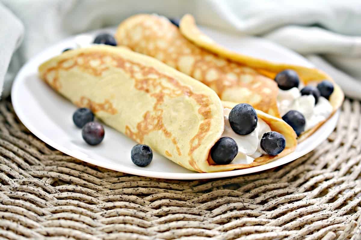 A plate of crepes with blueberries on it.