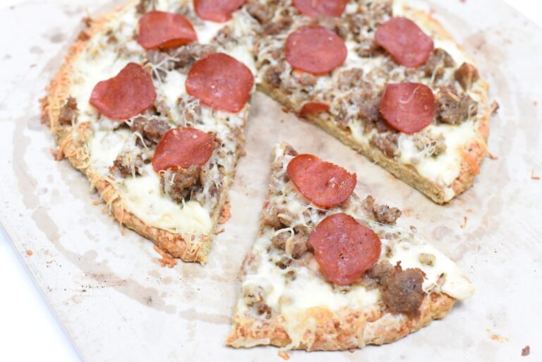 A pizza with pepperoni and sausage on a cutting board.