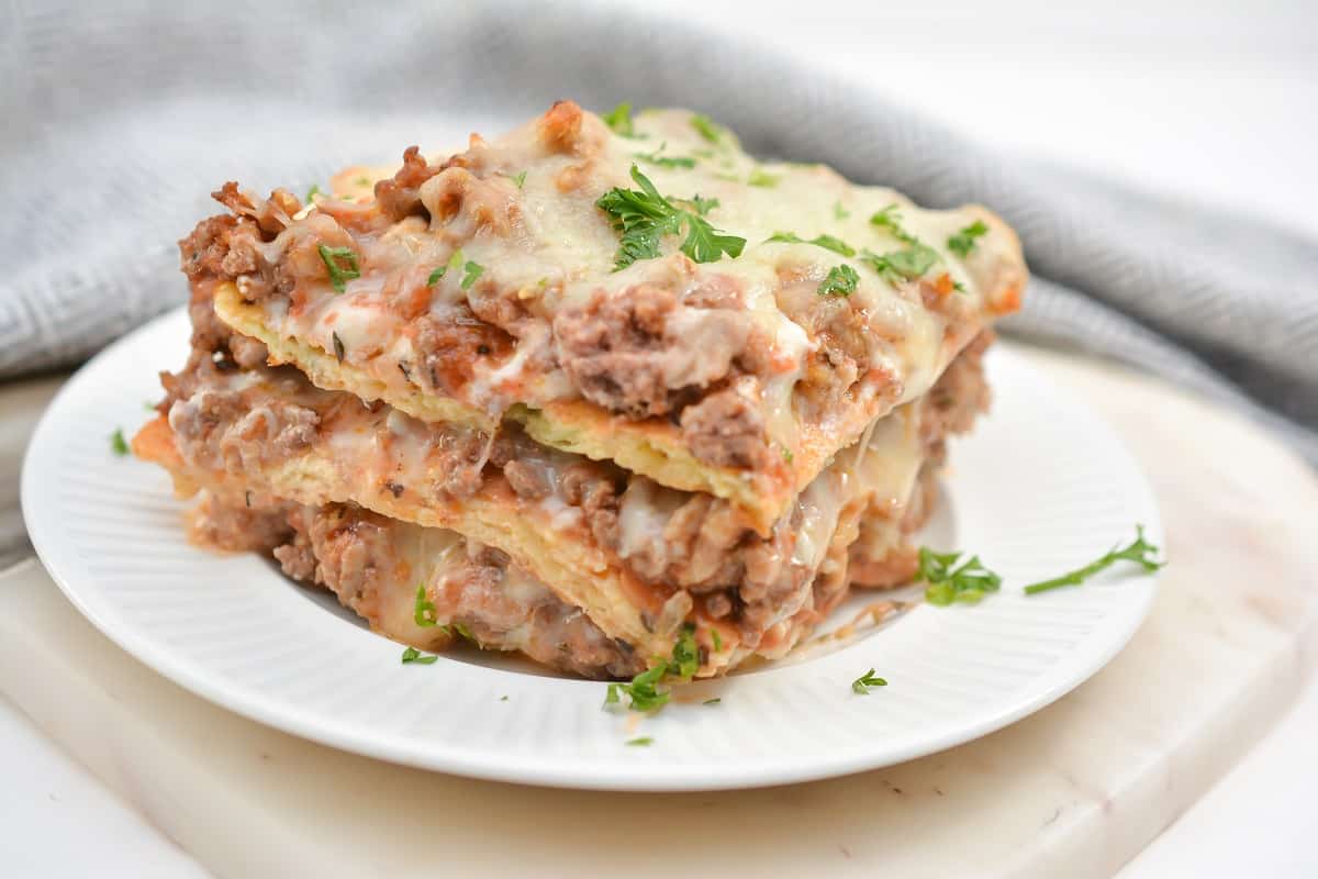 A stack of meat lasagna on a white plate.