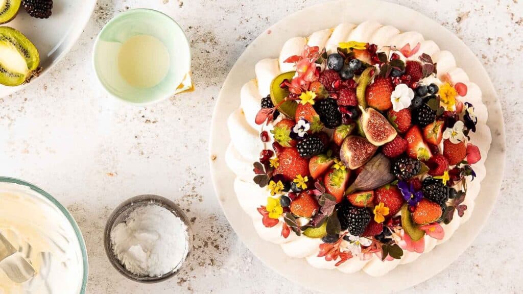 A pavlova with berries and fruit on a plate.