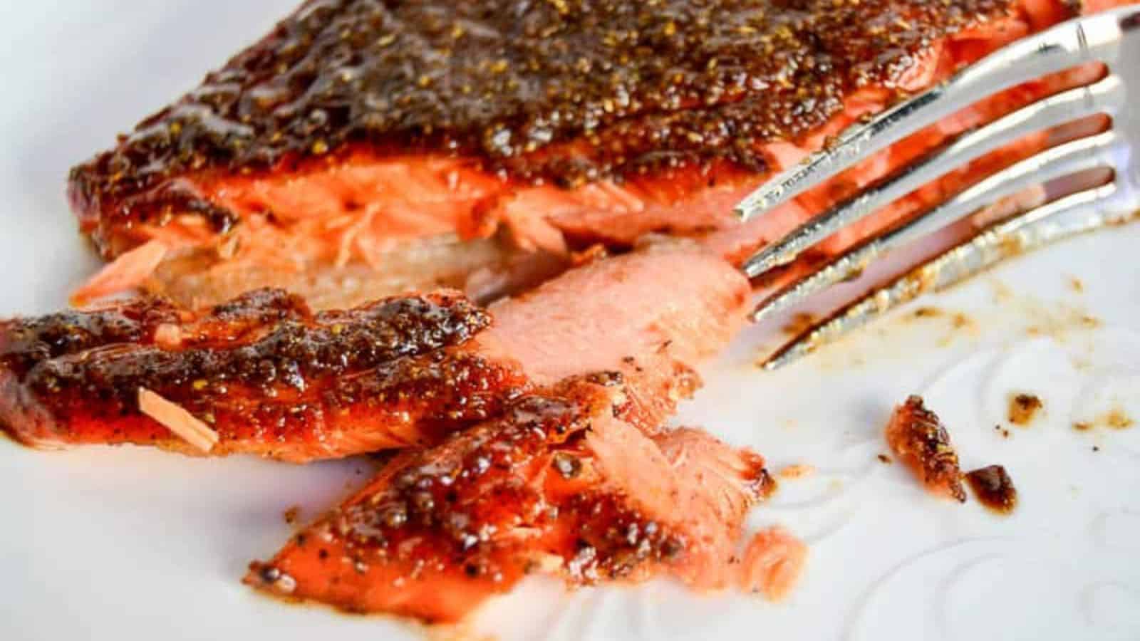 A piece of salmon on a plate with a fork.