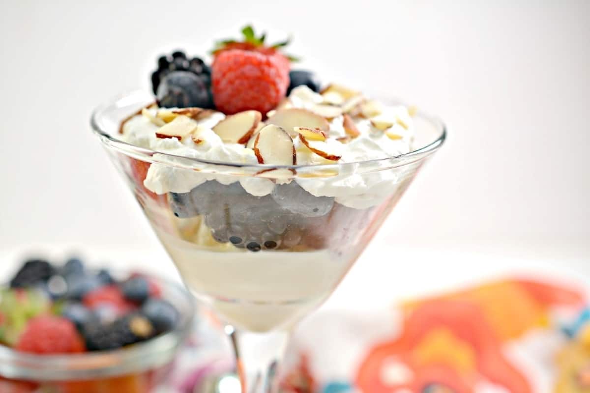 A glass filled with berries and whipped cream.