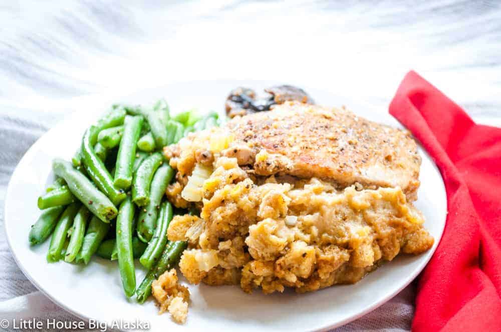 A stuffed chop on a plate with green beans.