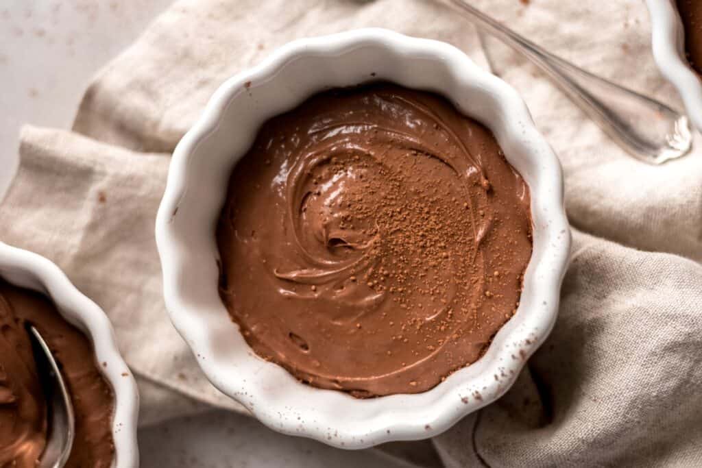 Chocolate pudding in white bowls with spoons.